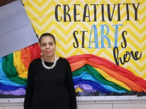picture of an African american lady standing in front of a multi-colored display board