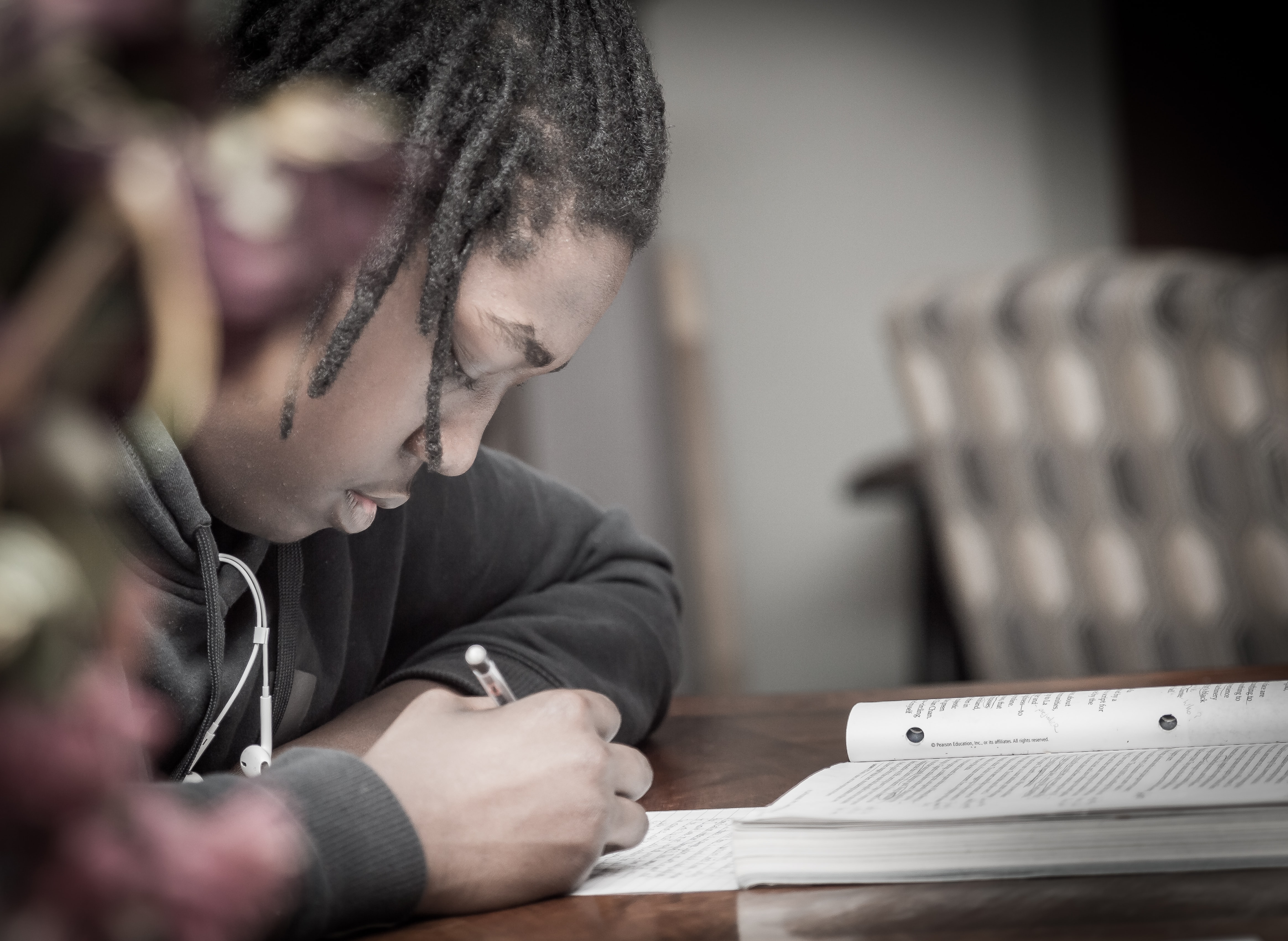 young black boy writing on paper near a desk