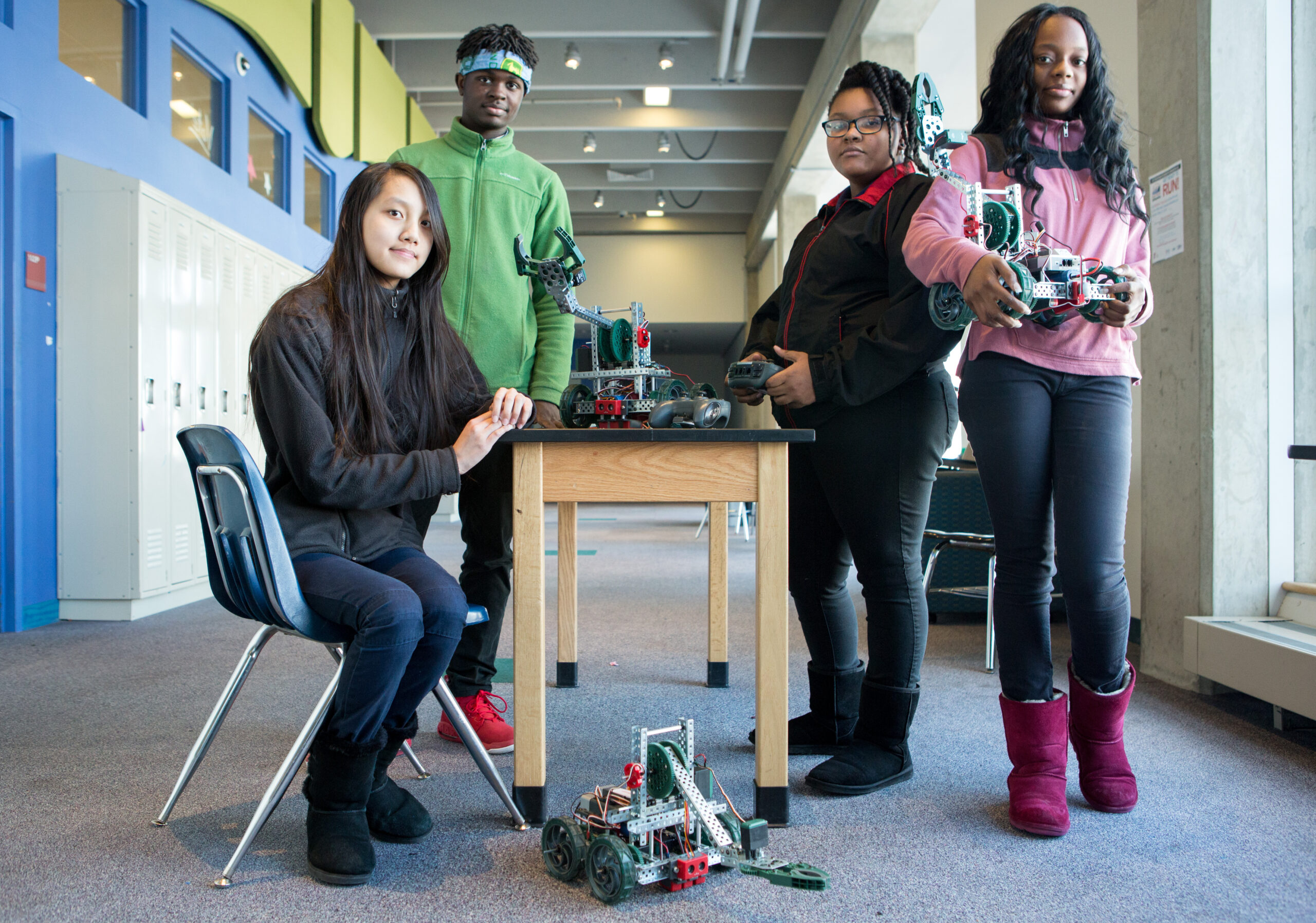 four students posing with their robot creations